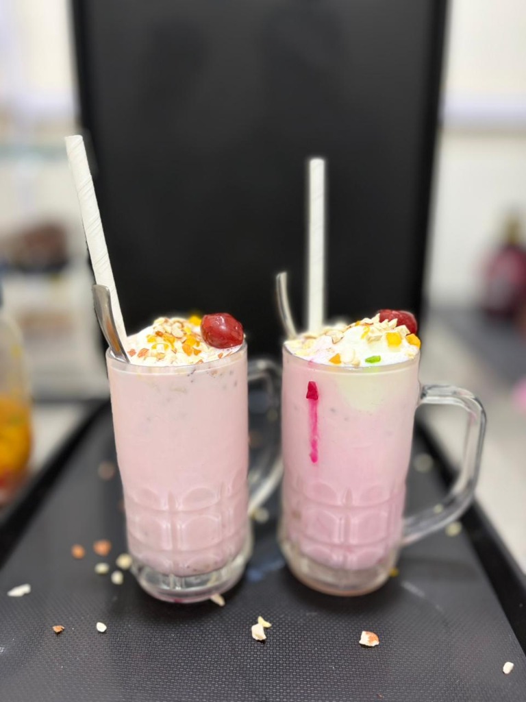 Twin pink rose milk shakes with cherry toppings